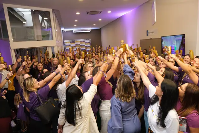 Plateia de camiseta roxa erguendo as mãos em direção ao palco