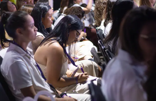 Participantes de branco atentas durante uma palestra